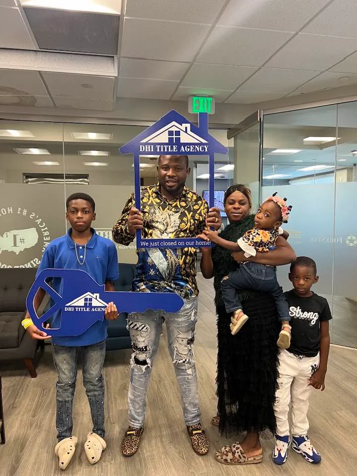 Family with children holding a giant key and a "We just closed on our home" frame at the title company